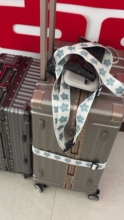 Printed strap on suitcase. Low-resolution original scene showing a printed strap fitted to a suitcase; reference only, not suitable for close-up zoom.
